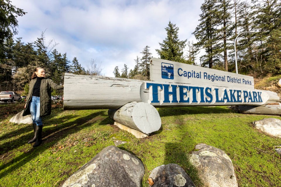 Lia Crowe with the Thetis Lake sign her father, Peter Martineau, carved in the 1980s. DARREN STONE, TIMES COLONIST 