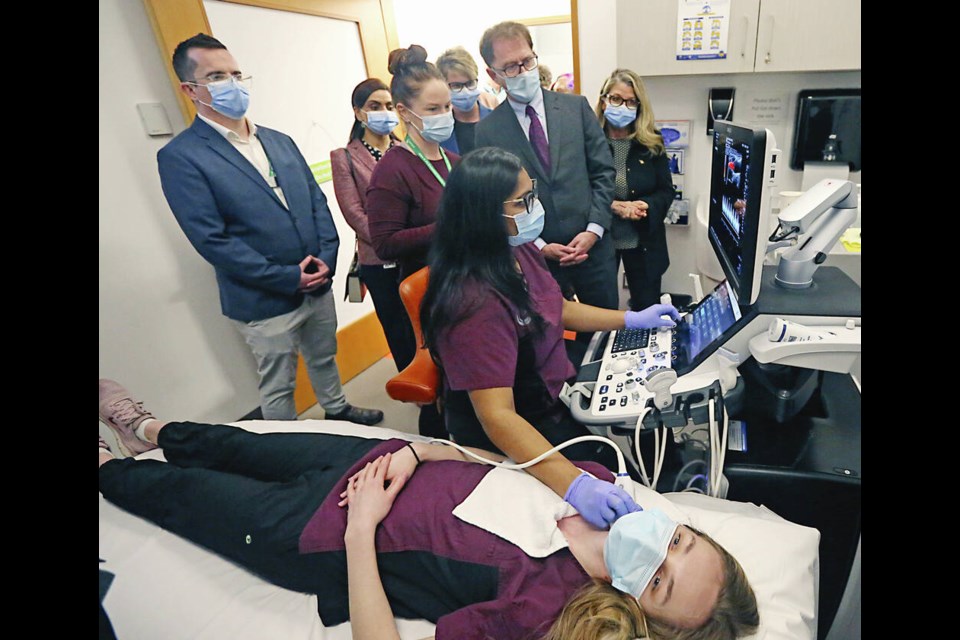 Instructor Jenn Lawless, second from left, with students Orthi Asselin, sitting, and Erin Edwards, lying down, shows how the system works to Health Minister Adrian Dix, center, and Lana Popham, back right, during an announcement of an ultrasound teaching clinic at Alex & Jo Campbell Centre for Health and Wellness at Camosun College. ADRIAN LAM, TIMES COLONIST 