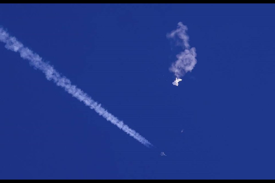 FILE - In this photo provided by Chad Fish, the remnants of a large balloon drift above the Atlantic Ocean, just off the coast of South Carolina, with a fighter jet and its contrail seen below it, Feb. 4, 2023. A missile fired on Feb. 5 by a U.S. F-22 off the Carolina coast ended the days-long flight of what the Biden administration says was a surveillance operation that took the Chinese balloon near U.S. military sites. It was an unprecedented incursion across U.S. territory for recent decades, and raised concerns among Americans about a possible escalation in spying and other challenges from rival China. (Chad Fish via AP, File)