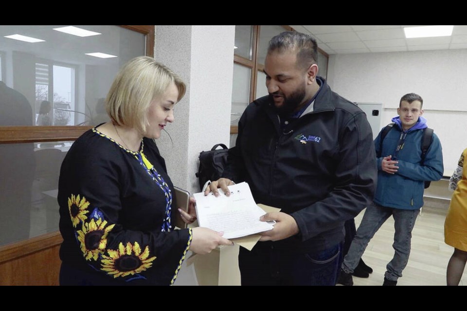 Svitlana Torbyk, left, a school principal at one of the Ukrainian schools where the team delivered supplies, accepts letters from a Grade 5 class at Willway Elementary School from Sooke School District chair Ravi Parmar. Via Brendan Strain 