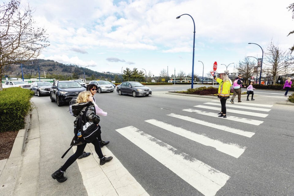 Crossing guard Kailey Sutherland helps students and parents cross West Shore Parkway after school on Wednesday. She says one of her colleagues has been bumped by a car there, and she is afraid of what could happen next. DARREN STONE, TIMES COLONIST 