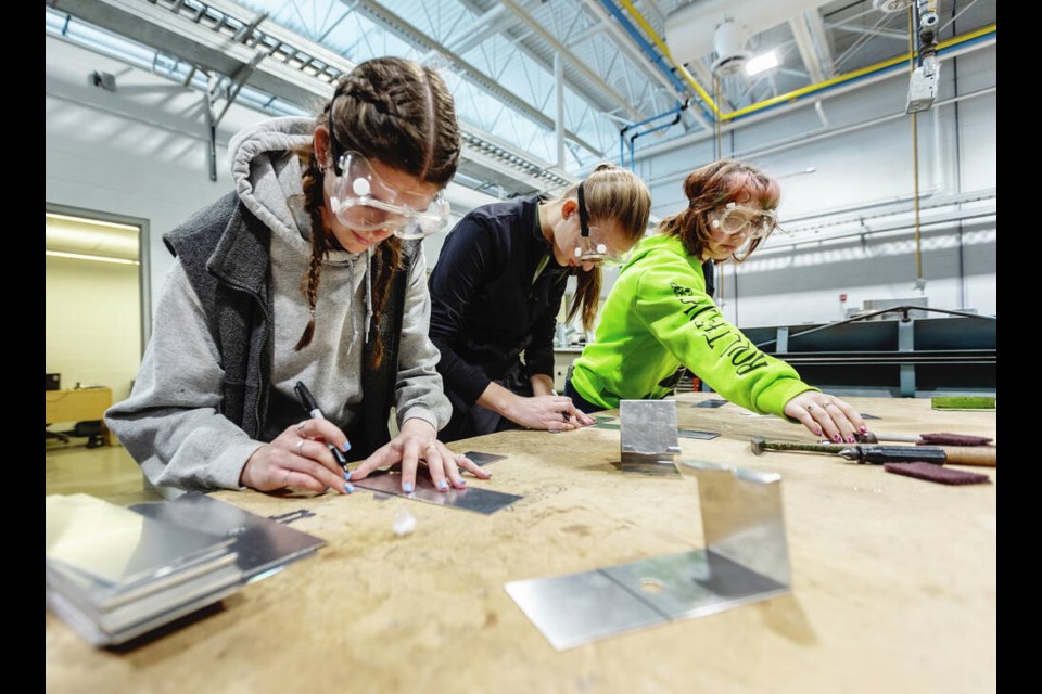From left, Kyla McLellan, Katie Walker-Duncan and Riley Colbourne make sheet metal cellphone holders at Camosun Colleges annual Women in Trades and Technology exploration day on Thursday. DARREN STONE, TIMES COLONIST 