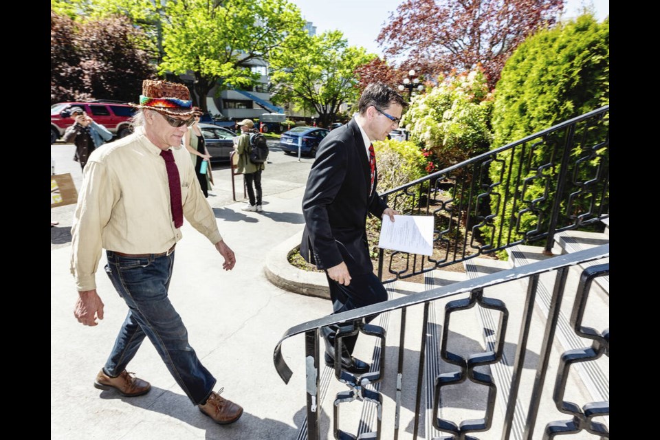 Ted Smith of the Victoria Cannabis Buyers Club Society, left, and lawyer Kirk Tousaw walk into the Victoria Courthouse to file a constitutional challenge against the province on Tuesday. DARREN STONE, TIMES COLONIST 