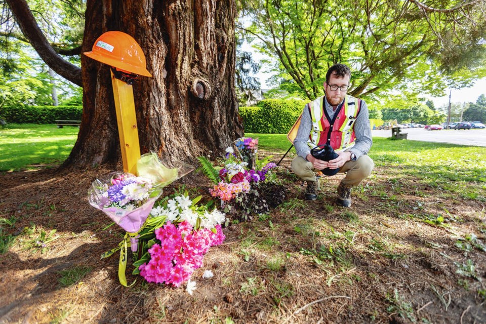 Steve Rennick, Oak Bay Public Works deputy director of engineering, pays his respects at a memorial site where worker Steve Seekins, seen at right, was killed Wednesday.  DARREN STONE, TIMES COLONIST 