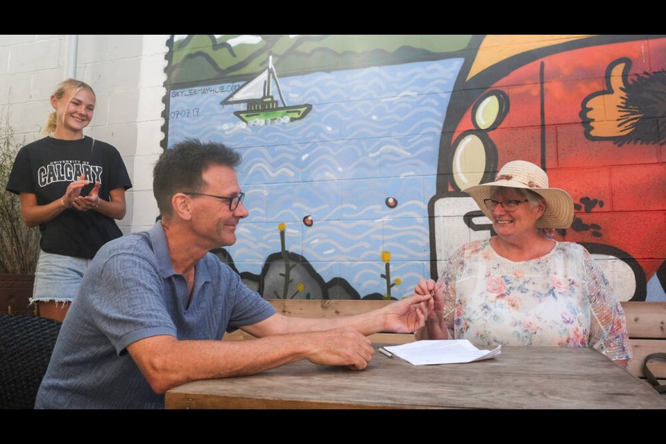 Stick in the Mud Coffee House owner David Evans hands over the keys to co-op president Wendy O’Conner after signing sale papers while his daughter Xanthe looks on. TIMES COLONIST 