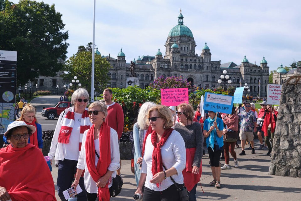 Attendees of the 4th Red Pashmina Walk in Victoria going past the legislature in Victoria. TIMES COLONIST 