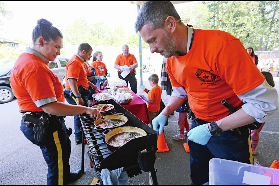 Const. Justina Webb, left, and Const. John Varley cook up a bannock treat for students at Savory Elementary in Langford on Friday. ADRIAN LAM, TIMES COLONIST 