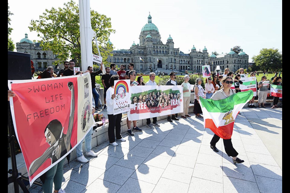 Nahid, right, carries an Iranian flag during a rally by members of Victoria’s Iranian community, at the B.C. legislature on Saturday. ADRIAN LAM, TIMES COLONIST 