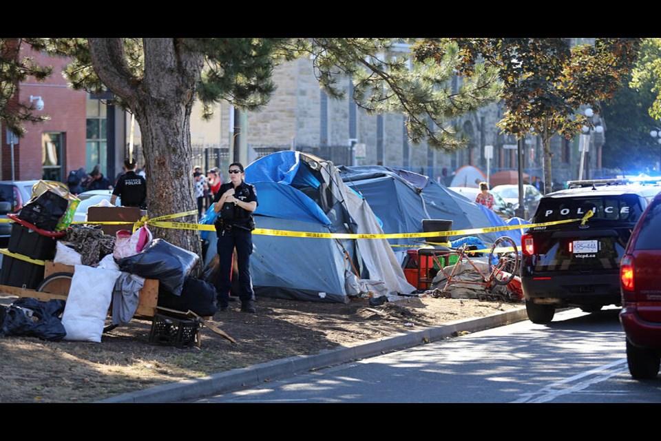 Victoria police officers stand guard in front a group of tents outside Our Place, as police look for evidence after a death near the corner of Vancouver and Pandora streets. ADRIAN LAM, TIMES COLONIST 