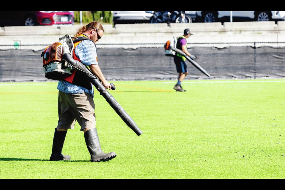 Workers use leaf blowers to clear debris from the shedding artificial turf at Oak Bay High School. The turf was installed three years ago. DARREN STONE, TIMES COLONIST 