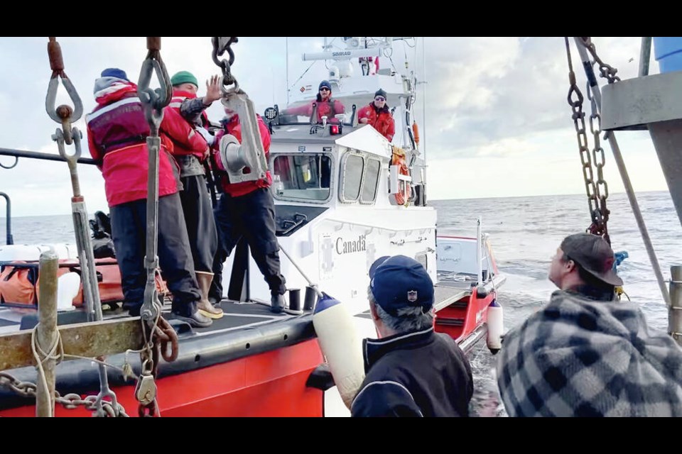 In an image taken from a video shared online by Ryan Planes, the rescued boater, in the green toque at left, waves to the crew that spotted his life raft 74 kilometres off Tofino. VIA RYAN PLANES 