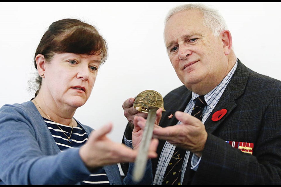 Curator Tatiana Robinson and volunteer Paul Seguna with the naval sword that is going on display today at the CFB Esquimalt Naval Museum. ADRIAN LAM, TIMES COLONIST