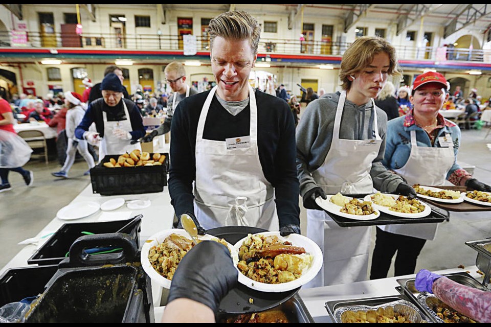 Saanich Mayor Dean Murdock, a server at the Mustard Seed’s Christmas luncheon, gets gravy added to some meals. ADRIAN LAM, TIMES COLONIST 