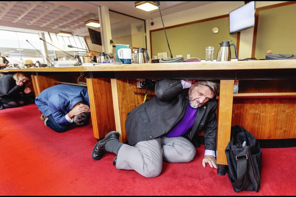 City of Victoria councillors, left to right, Jeremy Caradonna, left, and Chris Coleman do a “Drop, Cover, and Hold On" earthquake drill s part of the Great B.C. ShakeOut in Victoria on Oct. 19, 2023. DARREN STONE, TIMES COLONIST




