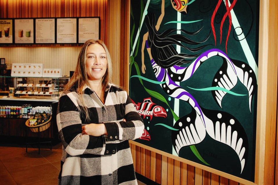Jessica Chickite stands next to her painting created for the We Wai Kai licensed-Starbucks store near Campbell River, which opened last week. VIA STARBUCKS CANADA 