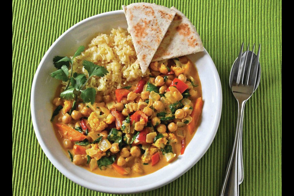 Madras-style vegetable curry is rich with chickpeas and vegetables and served with lime, coconut rice and naan.  ERIC AKIS