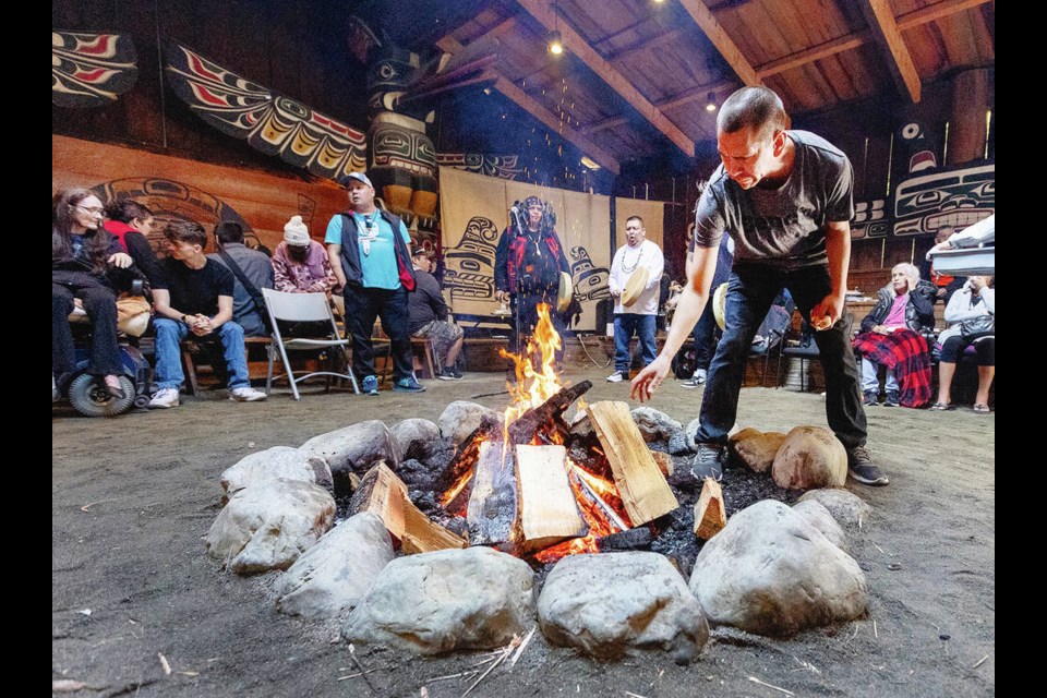 Ian Charleson adds wood to the ceremonial fire during an Indigenous Outreach Workers culture day organized by several service providers, at Mungo Martin House in Victoria on Monday. DARREN STONE, TIMES COLONIST 
