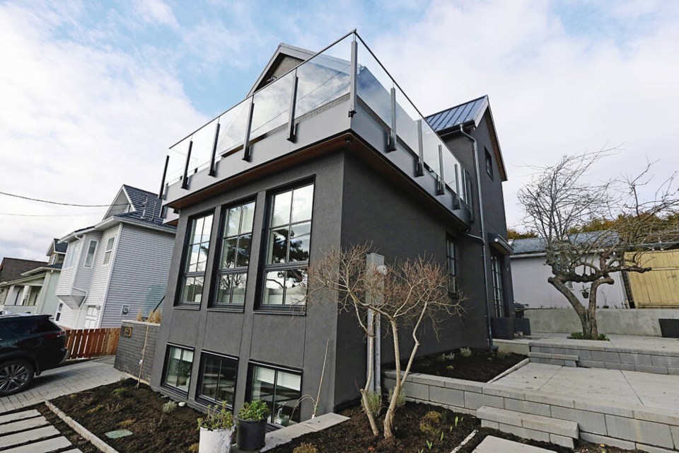 The modern home is immediately adjacent to the older heritage-style house that can be seen in the background. The new three-level house is designed to provide space for multi-generational living.  