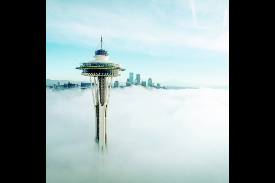 The top of Seattle’s Space Needle is seen above the clouds, in a photo that also shows some of the renovations to the 62-year-old Seattle landmark, which includes tilted open air glass panels on the top observation deck. The next renovation phase is updating its three elevators. SPACE NEEDLE 