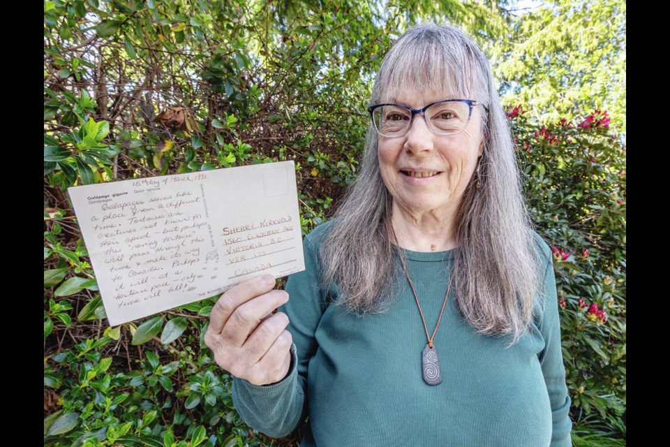 Sherry Kirkvold with the postcard she left in a whale-oil-barrel post box on the Galapagos Islands in 1991. DARREN STONE, TIMES COLONIST 