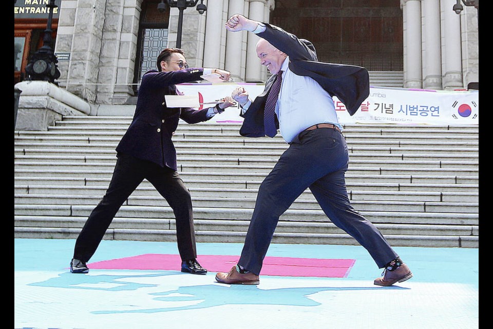 Then -premier John Horgan, right, breaks a board held by Mike Suk, executive director of the Korean Cultural Heritage Society, to help celebrate B.C. Taekwondo Day in 2017. ADRIAN LAM, TIMES COLONIST 