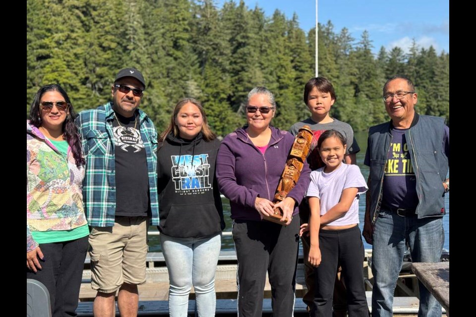 Pam London and Sonj Bunwait, left, with Shelley Edgar, holding the pole carved by her late grandfather Joe Shaw, and her family. COURTESY SHELLEY EDGAR 