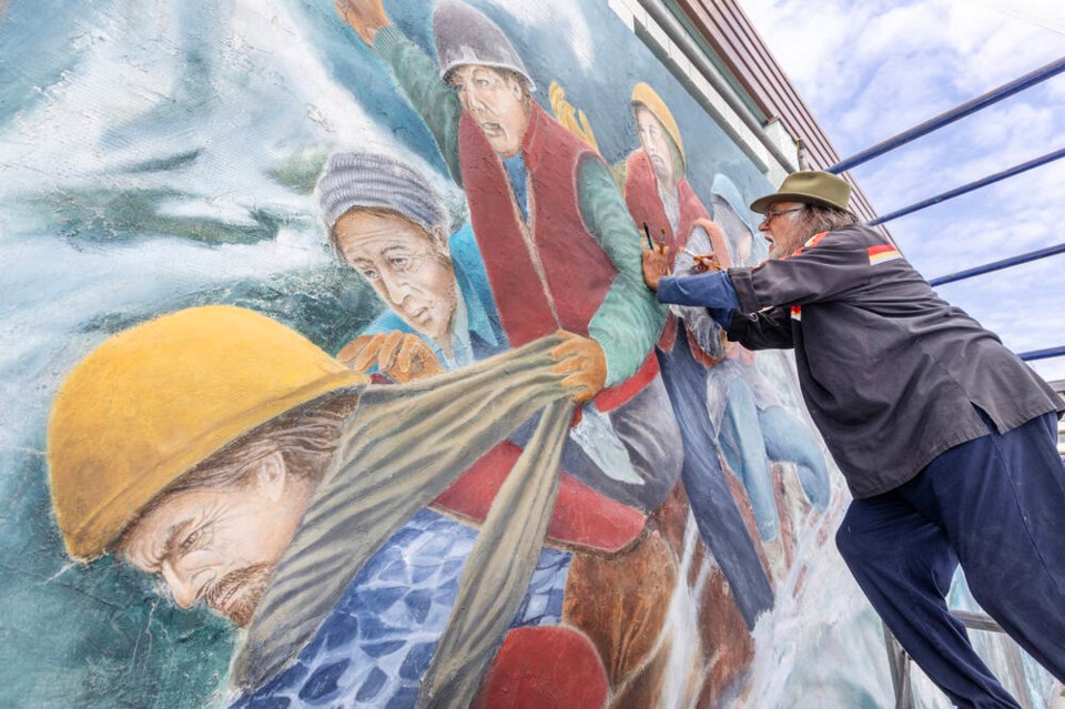 Artist IceBear works on The Ocean mural on the side of Fairway Market in Sidney on Friday. The restoration project includes cleaning and repainting the mural, which was commissioned to mark International Year of the Ocean in 1999. DARREN STONE, TIMES COLONIST