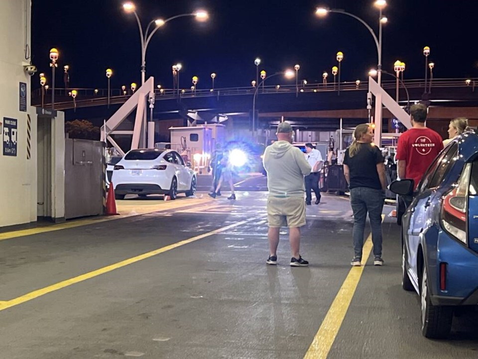 The driver of a white Tesla, at left, was arrested on several charges after attempting to drive his vehicle off a B.C. ferry from Mayne Island on Canada Day. The man was taken into custody at Swartz Bay terminal at about 11:30 on Tuesday. MARTIN FARNHAM