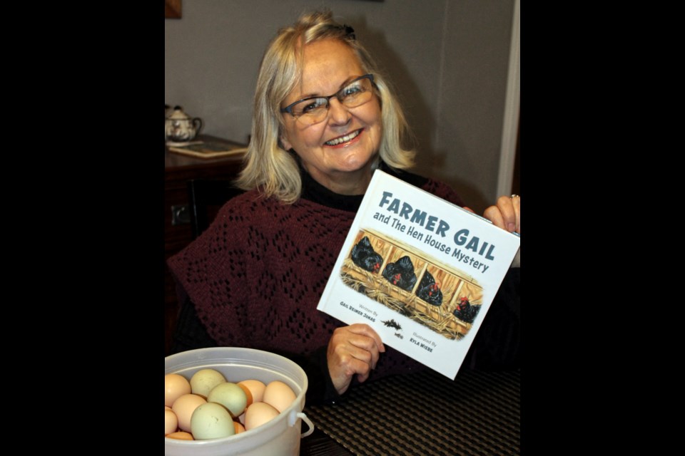Gail Jonas with a copy of her new book Farmer Gail and The Hen House Mystery and a pail of freshly gathered eggs.