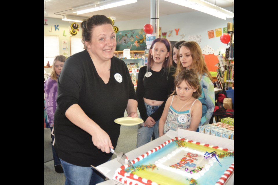 Children's Clerk Alyssa Eisner serves up pieces of Dr. Seuss' birthday cake  (donated by Valleyview Co-op) 
 to young patrons.