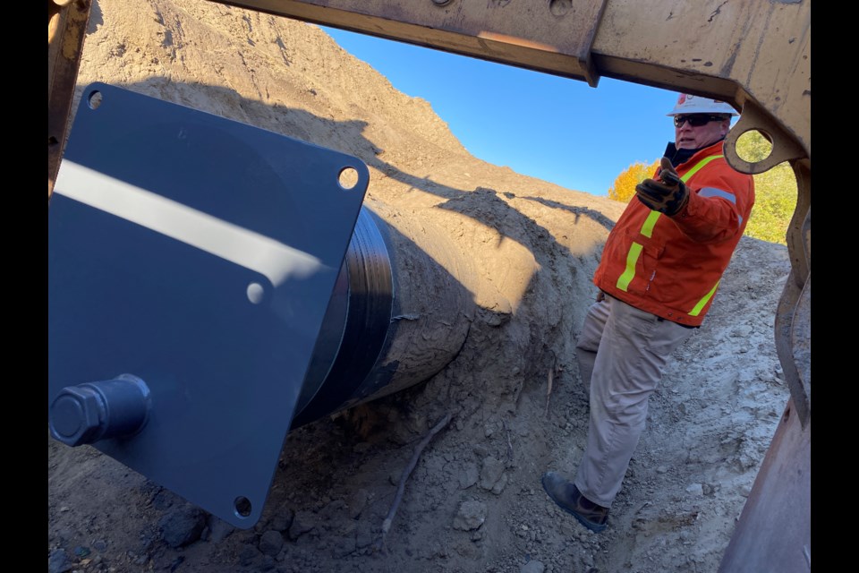 1. Inspector Sandy Armstrong shows a section of pipe following installation of a steel cap. After the pipe segment is cut, a cap is fabricated onto the ends of the pipe and coated with epoxy. This permanently seals the pipeline at that location and backfill can then be completed.