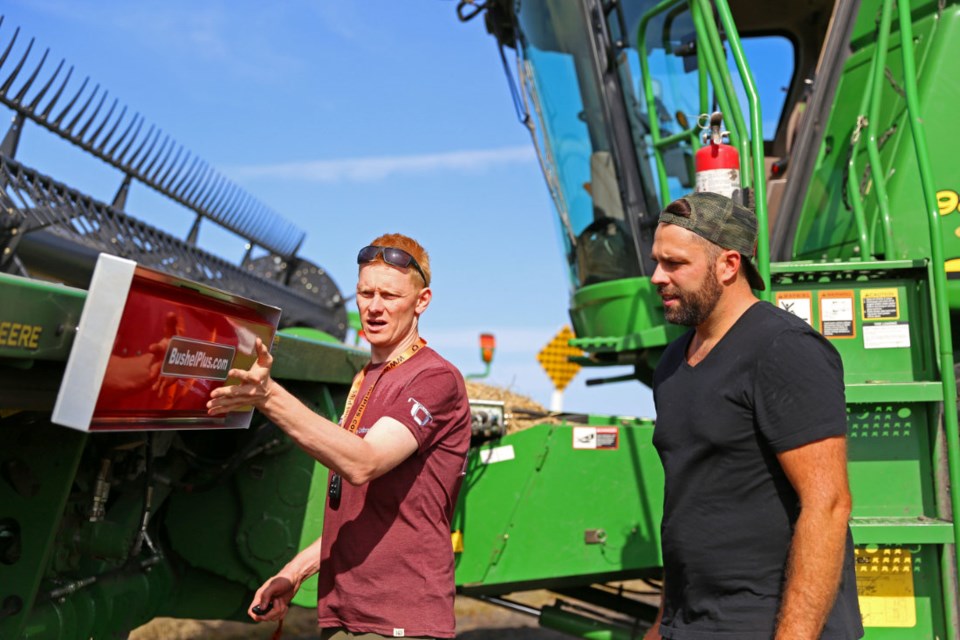 Marcel Kringe (l), founder and CEO of Bushel Plus demonstrates how the Drop Pan magnetic system attaches to a combine.