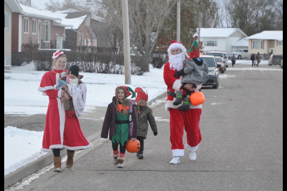 Kaylee, left, and Matt McLean, dressed as Santa and Mrs Claus, and their kids make their way along Scarth Drive while trick-or-treating.