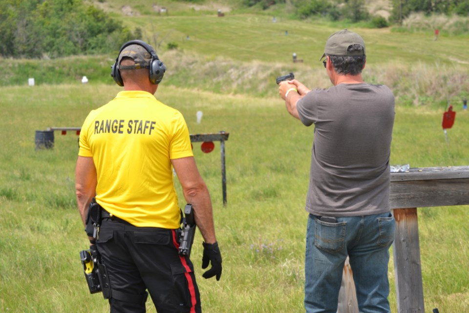 Range officer Joe Frizzley (l) watches as a visitor to the Wolverine Days open house tries out a 9 mm handgun.  
