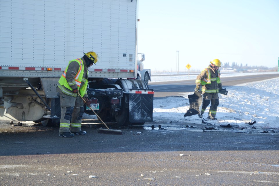 CRASH CLEANUP - Firefighters sweep up debris following a two-vehicle accident at the intersection of Highway 1 and 83 N. on Dec. 21. The collision is under investigation by the RCMP. 