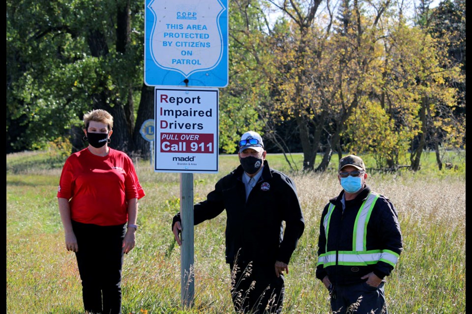 Vicki Renwick (l) representing Brandon and Area MADD, stands at one of four the recently installed “Call 911 to report…” signs, along with Mayor of Virden Murray Wright
and Town foreman Maurice Kernel (r).