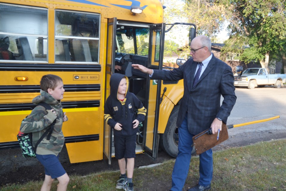 Brad Hayward, Principal of Mary Montgomery School, with clipboard and walkie-talkie in hand, greets students as they exit their bus on Sept. 6, on the first day of the school year.
