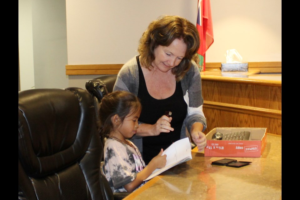In Council chmabers, CAO Rhonda Stewart stamps each student's passports.