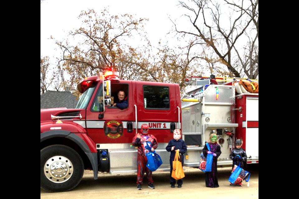 Chief Nick Young and firefighter Ryan Brown of the Miniota Fire Department on patrol with trick or treaters Connor, Jaxon, Rory and Easton.