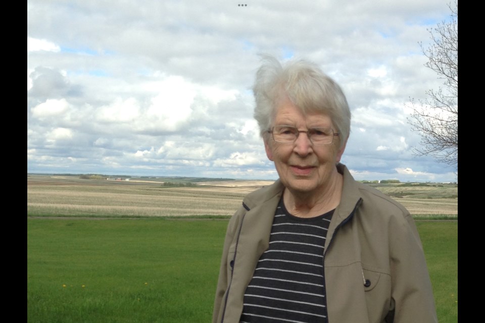 Roma Stevenson stands with the farm’s rolling fields behind her.