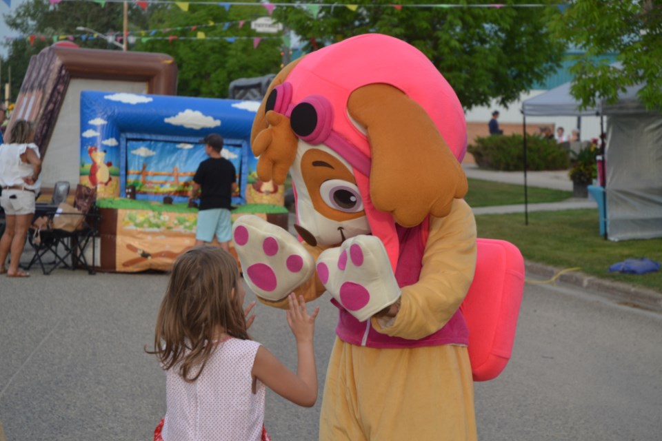 Friday evening Aug. 4, at Elkhorn Homecoming street carnival a young fan high-fives a Paw Patrol mascot at the Elkhorn Chamber of Commerce event.