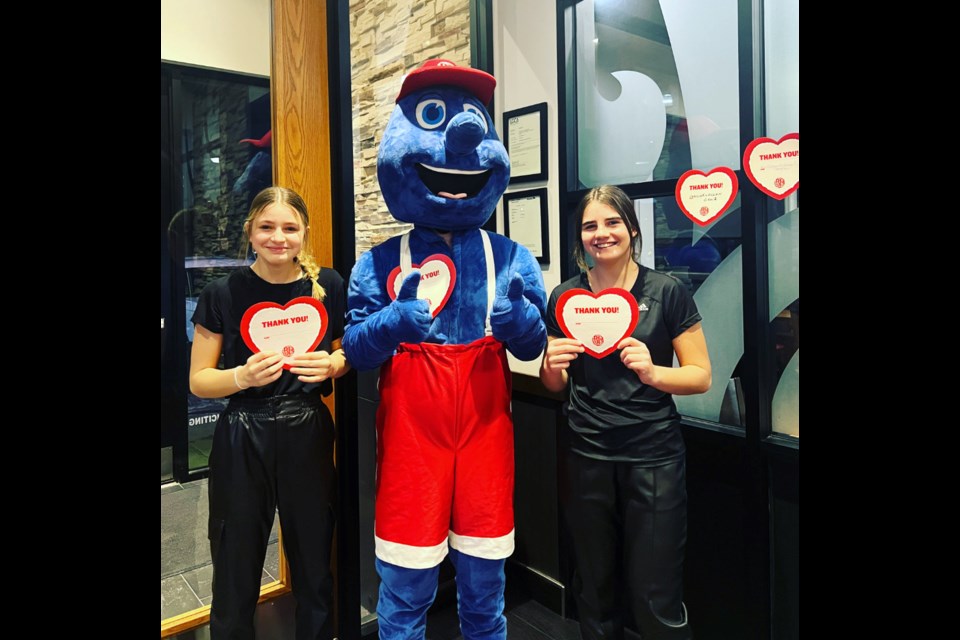 Boston Pizza Hosts promoting heart sales: Libby Verran and Sadie Brown posing with the BP mascot Lionel. 