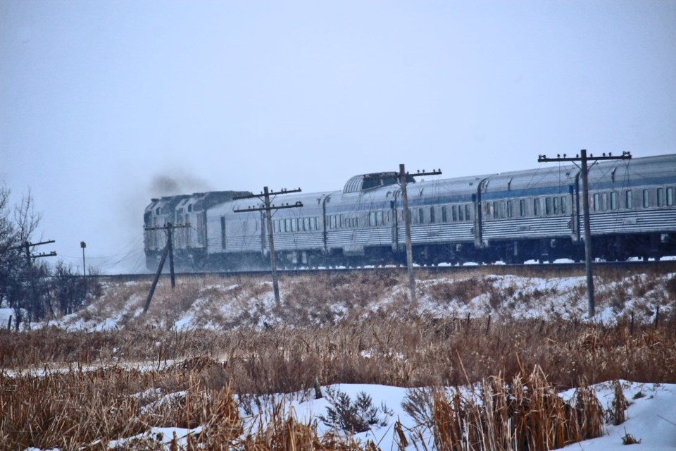 VIA rail’s transcontinental passenger train, “The Canadian”, heads east near Arrow River, Manitoba on Feb. 19, 2023, seen through the remains of the original telegraph/telephone lines that followed the rail line. These communication lines have been out of use for decades. 