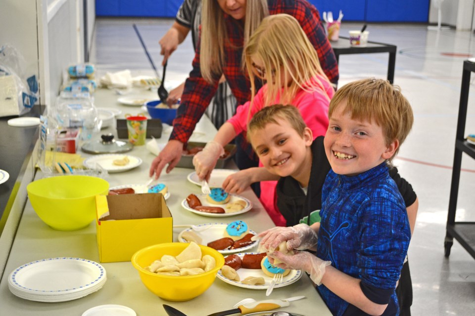 711 Kinsley Robertson (l), Kale Kliever and Rowan Darvill, Grade 3 students at Goulter School, help prepare plates of Ukranian food during the hot lunch fundraiser on May 12. The school's grade 3 classes hosted the meal of perogies, farmer's sausage and cookies and the $900.00 raised was sent to the Ukranian Canadian Association Tryzub. Valleyview Consumers Co-op donated food for the cause.