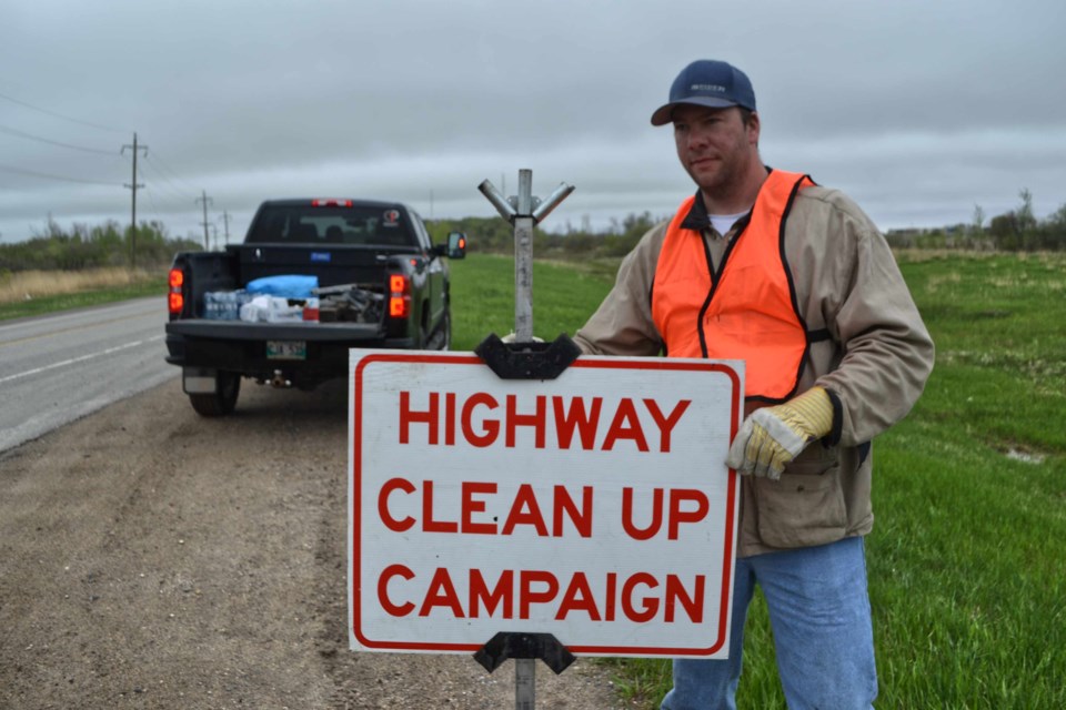 4-H Leader Curtis Wolters sets up a sign near the Silverline Oilfield Services building on Highway 83 to warn motorists of the Highway Clean Up campaign