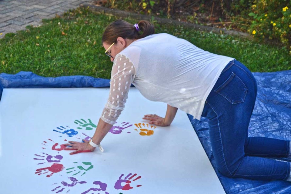  Tiffany Cameron, Chair of the Virden Boost Committee, adds her handprint to an art board which will be placed in the Nelson Street Park. It reads "We are each unique and beautiful, but together we are a masterpiece." 