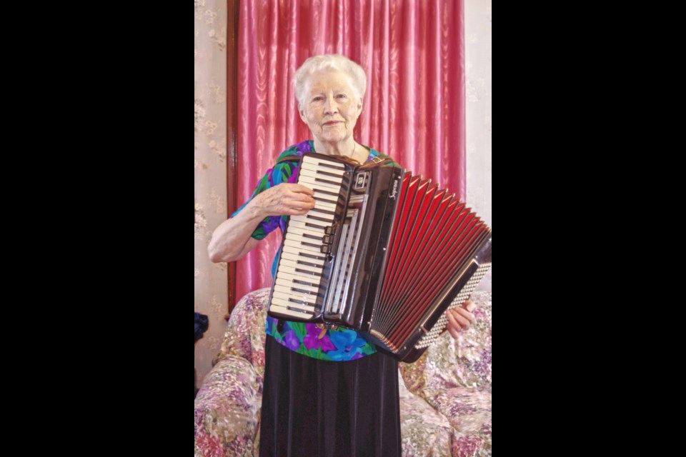 Norma playing the accordion and piano at her home in Souris, Man.  