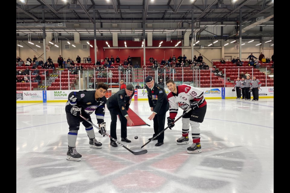 The command team from the Canadian Forces Base Shilo – Lieutenant-Colonel Christopher Wood (right) and Chief Warrant Officer Jeremy Abrahamse - participate in the evening’s ceremonial puck drop; at centre ice OCN Blizzard Riley Zimmerman (l), and for the Oil Caps Brodie Wilson.