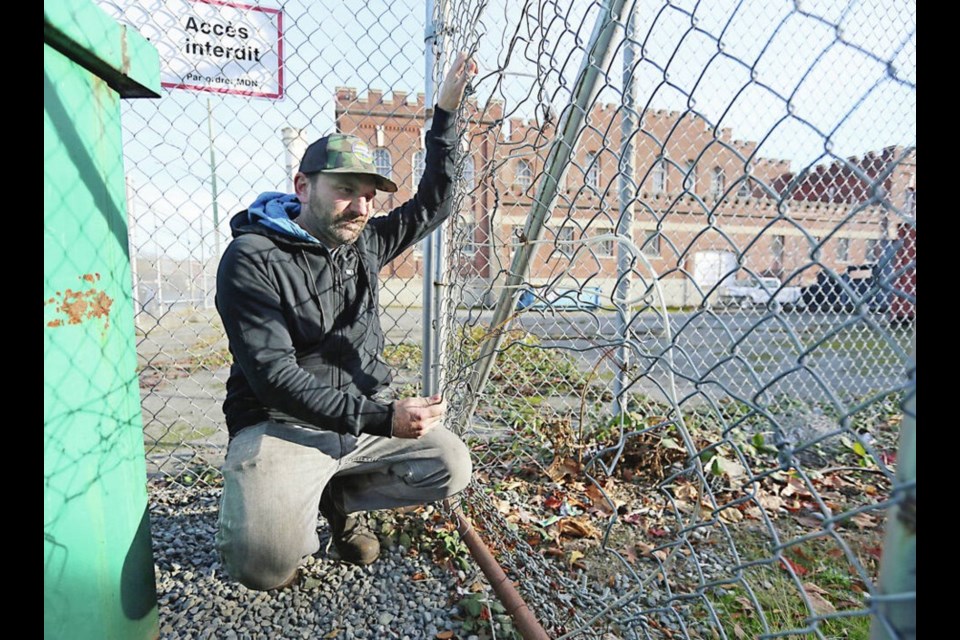 Ryan Burghardt, owner of Budget Brake and Muffler, shows where a fence around his yard had been cut. Staff have been threatened, vehicles damaged and items stolen. | Adrian Lam, Times Colonist 
