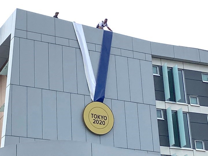Workers hang giant medal to honour Christine Sinclair. | Burnaby Now 

